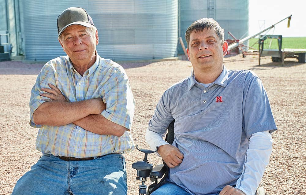 Bob and Eric Beckman sitting in front of grain bins on a sunny day