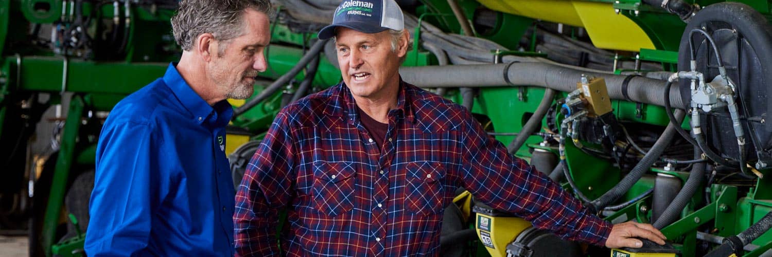 two men talking near farm equipment