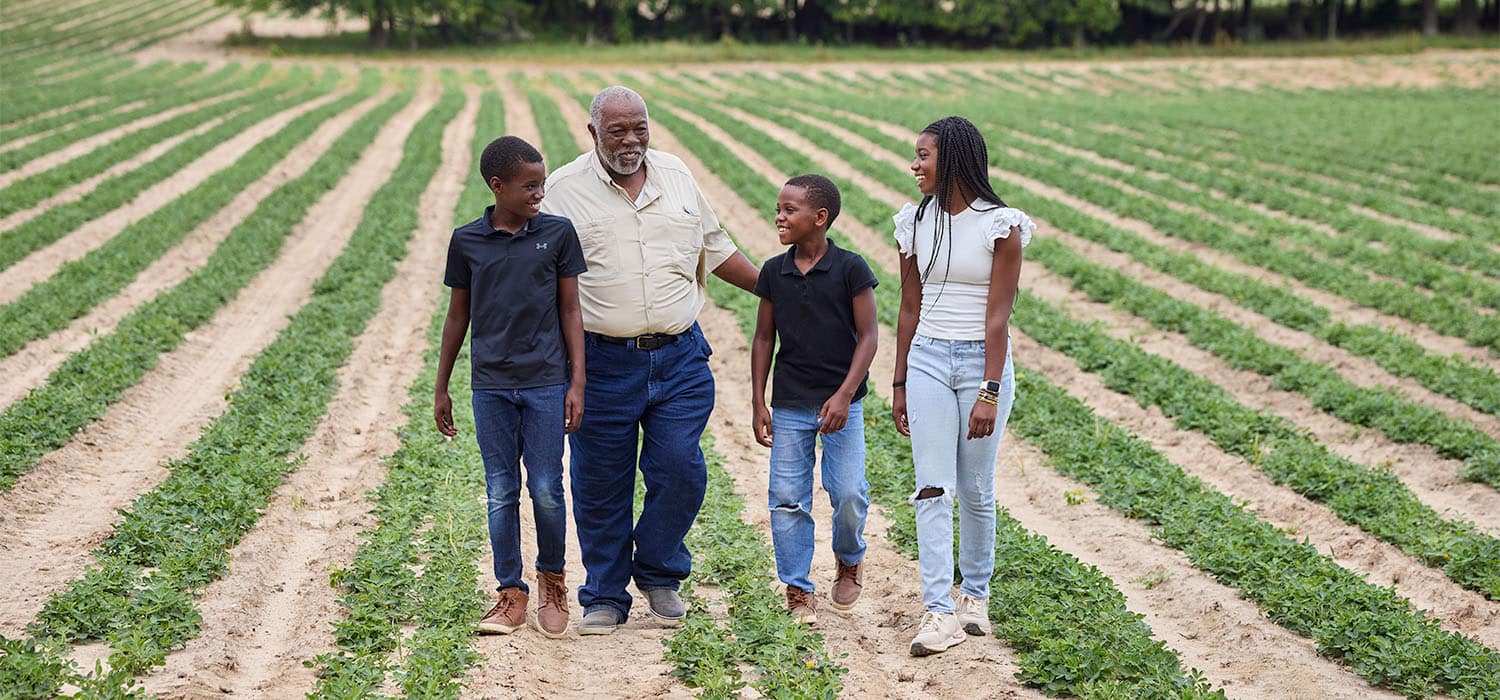 Producer Howard Hodge and his three grandkids walking through farmland