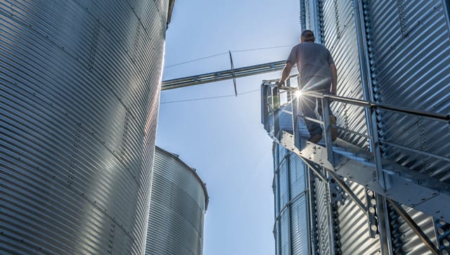 producer walking up stairs on the side of a grain bin