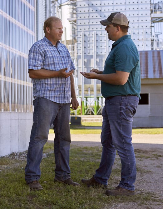 ADM rep talking to farmer next to grain bin