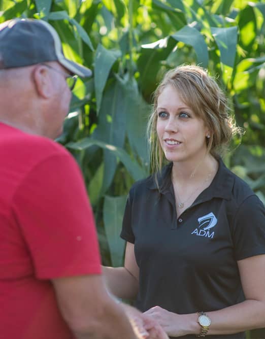 Female ADM representative talking to male farmer in corn field