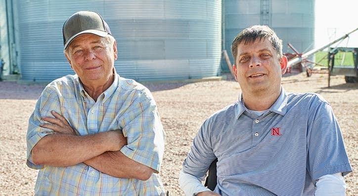 Two producers smiling with grain bins in background